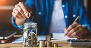 A_man_putting_money_in_a_jar_savings.width-800